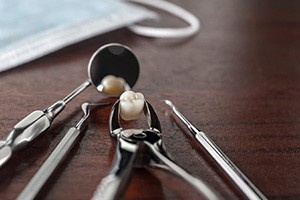 Extracted tooth and dental instruments on wooden surface