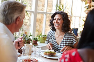 Woman smiling while eating with friends in restaurant