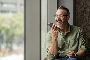 Man with glasses smiling while talking on phone
