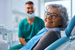 Woman with black glasses smiling in treatment chair