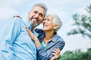 Senior couple smiling while hugging outside