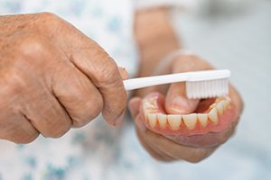 Patient cleaning denture with toothbrush