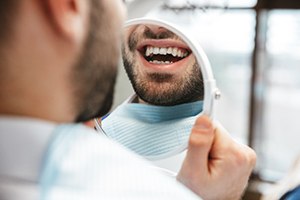 Man’s imperfect smile reflected in handheld mirror