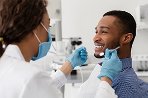 Cosmetic dentist using tools to examine patient's smile