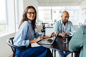 Woman smiling while sitting at desk with colleagues