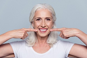 woman with dental implants in Rockville pointing to her smile