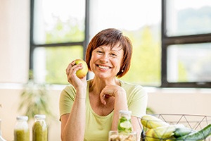 woman sitting at a table and holding an apple