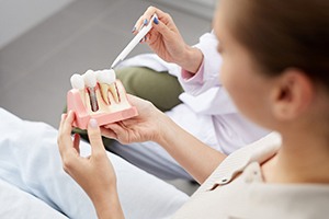 dentist showing a dental implant model to a patient