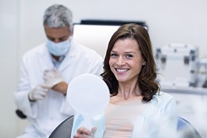 smiling dental patient holding a mirror