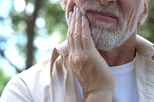 Distressed man holding his jaw in pain