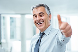 Business man smiling and giving thumbs up 
