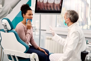 a dentist speaking with a patient while they hold an icepack against their face