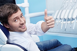 Male dental patient in white shirt giving thumbs up