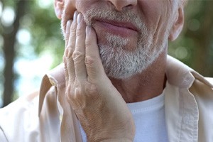 Man with oral pain rubbing his jaw