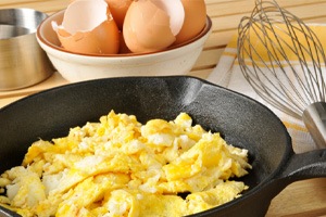 Scrambled eggs in a frying pan on wooden table
