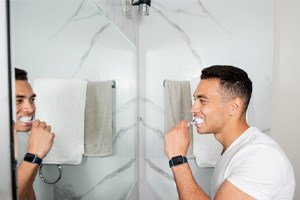 Man brushing his teeth in the bathroom mirror