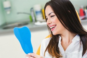 Female patient checking her smile in handheld mirror 