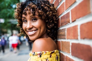 person standing against a brick wall and smiling