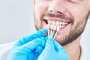 dentist holding veneers up to a patient’s smile