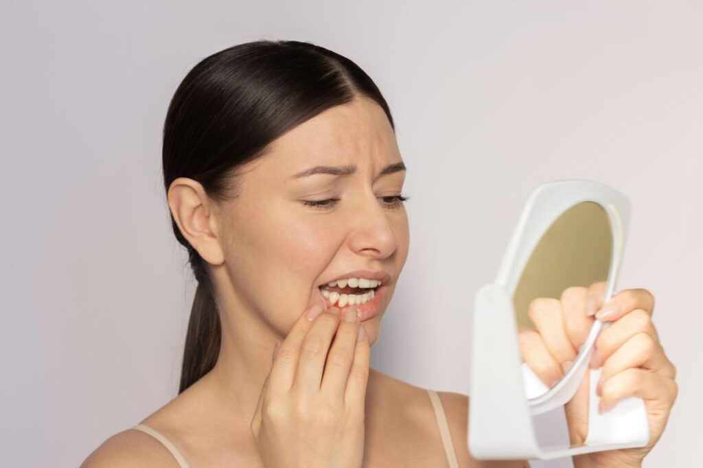 A woman looking at a bump on her gums